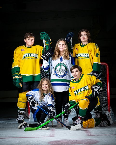 Boys and girls hockey buddy sports portrait. Two girls, three boys in front of a hockey goal. 