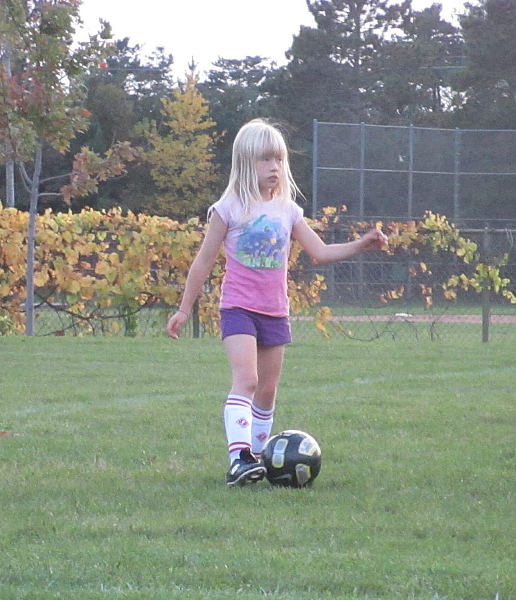 Childhood photo of Taylor playing soccer outside
