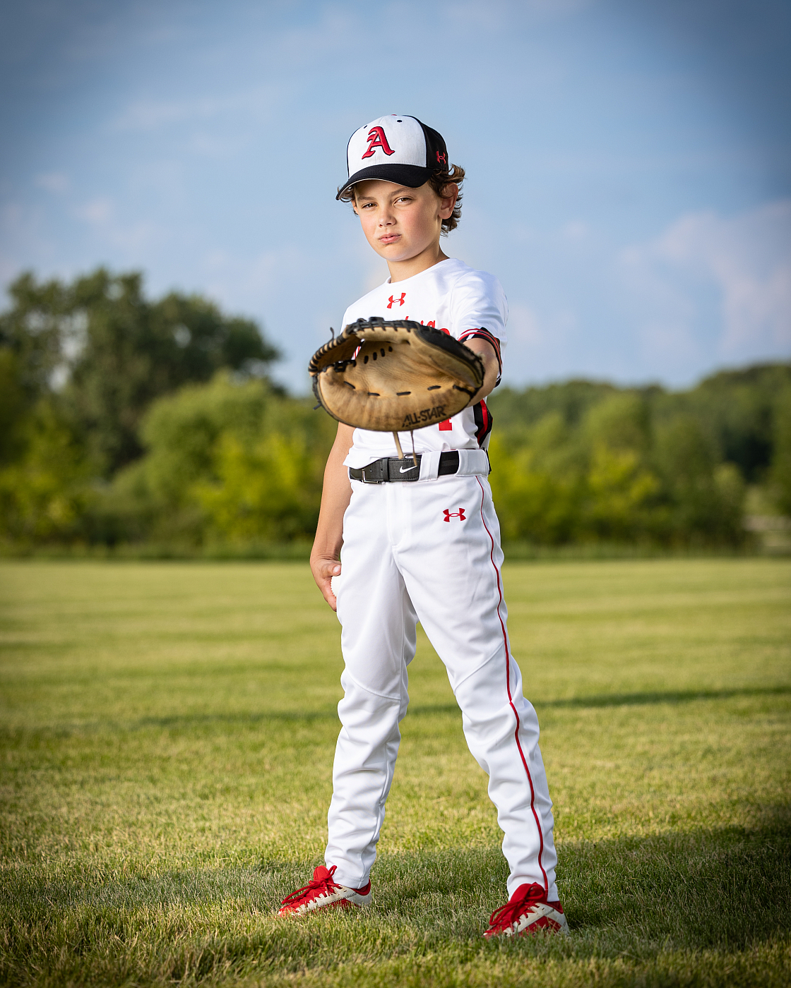 Boy holding out baseball glove in baseball portrait.