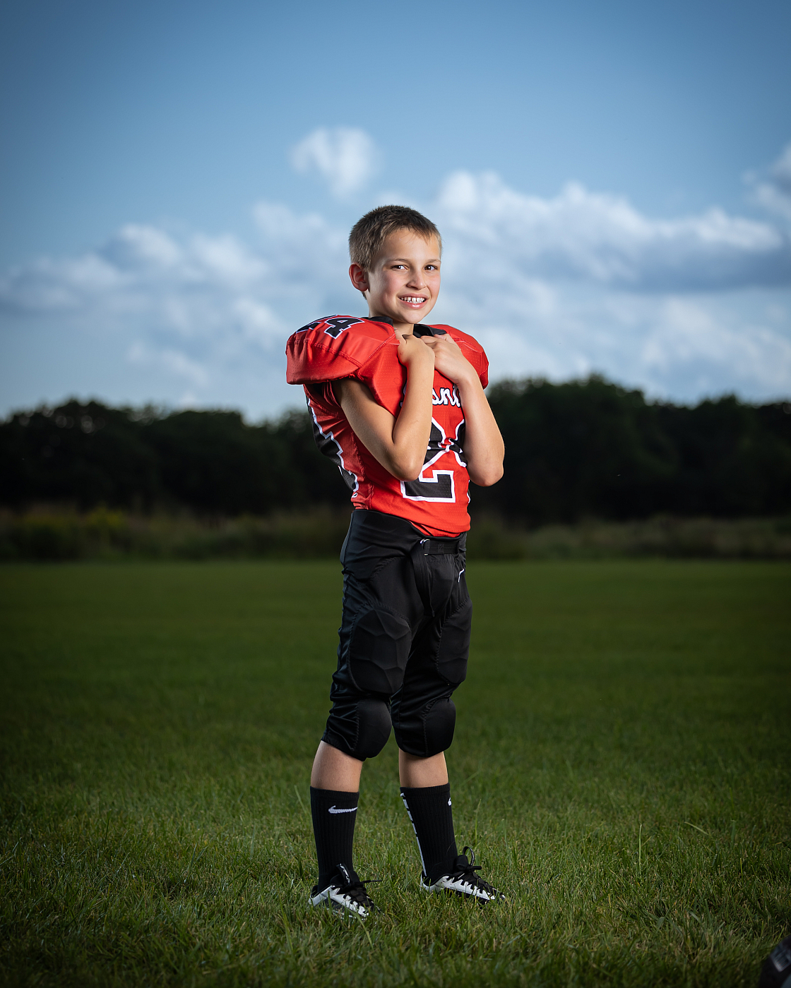 Little boy in orange and black football uniform outdoor sports portrait.