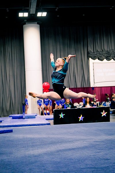 high school girl split leap on gymnastics floor