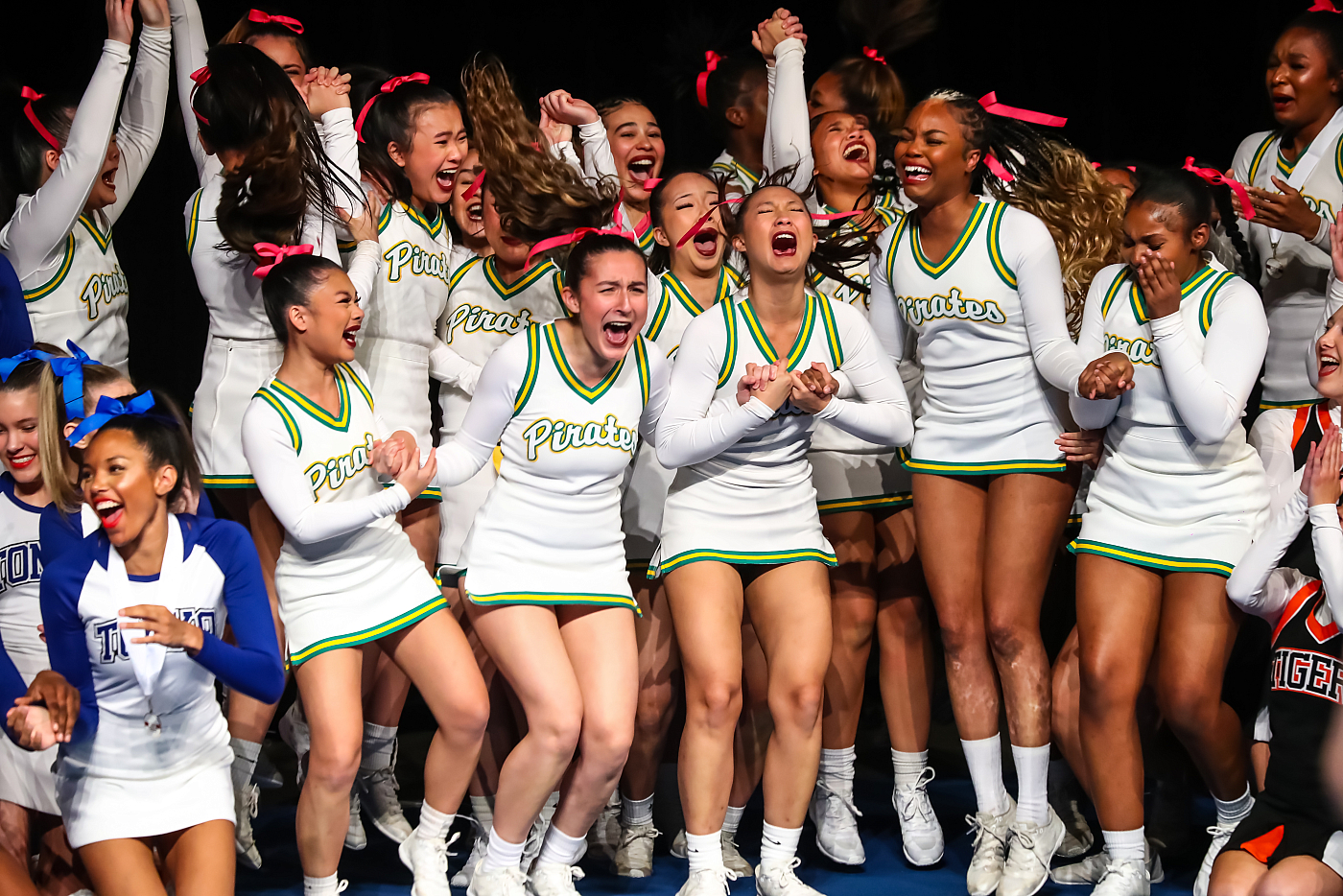 girls cheerleading team celebrating at competition white, yellow, green uninforms