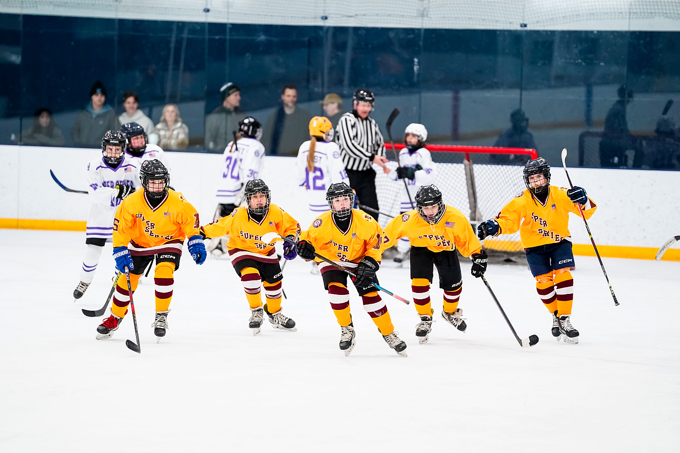 five boy hockey players skating on ice yellow uniforms super series