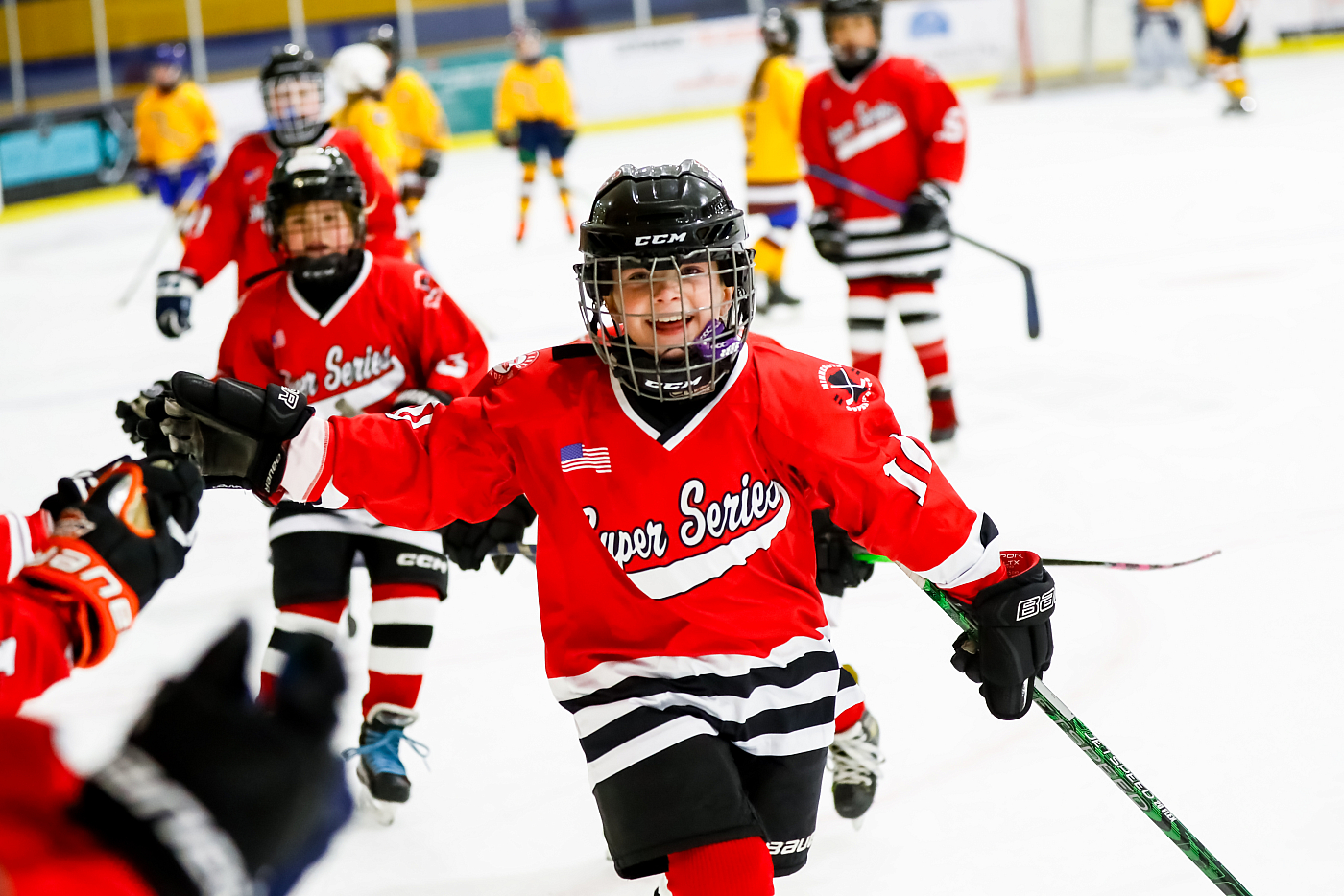 boy hockey player in red jersey gives high five to coach