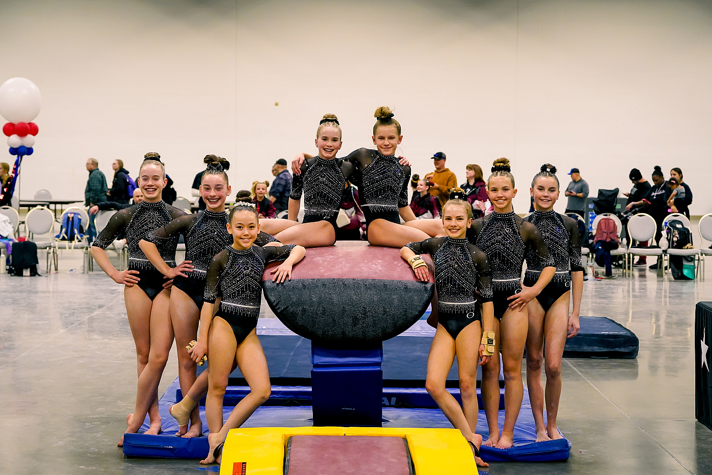 girls gymnastics team posing on vault in black leotards