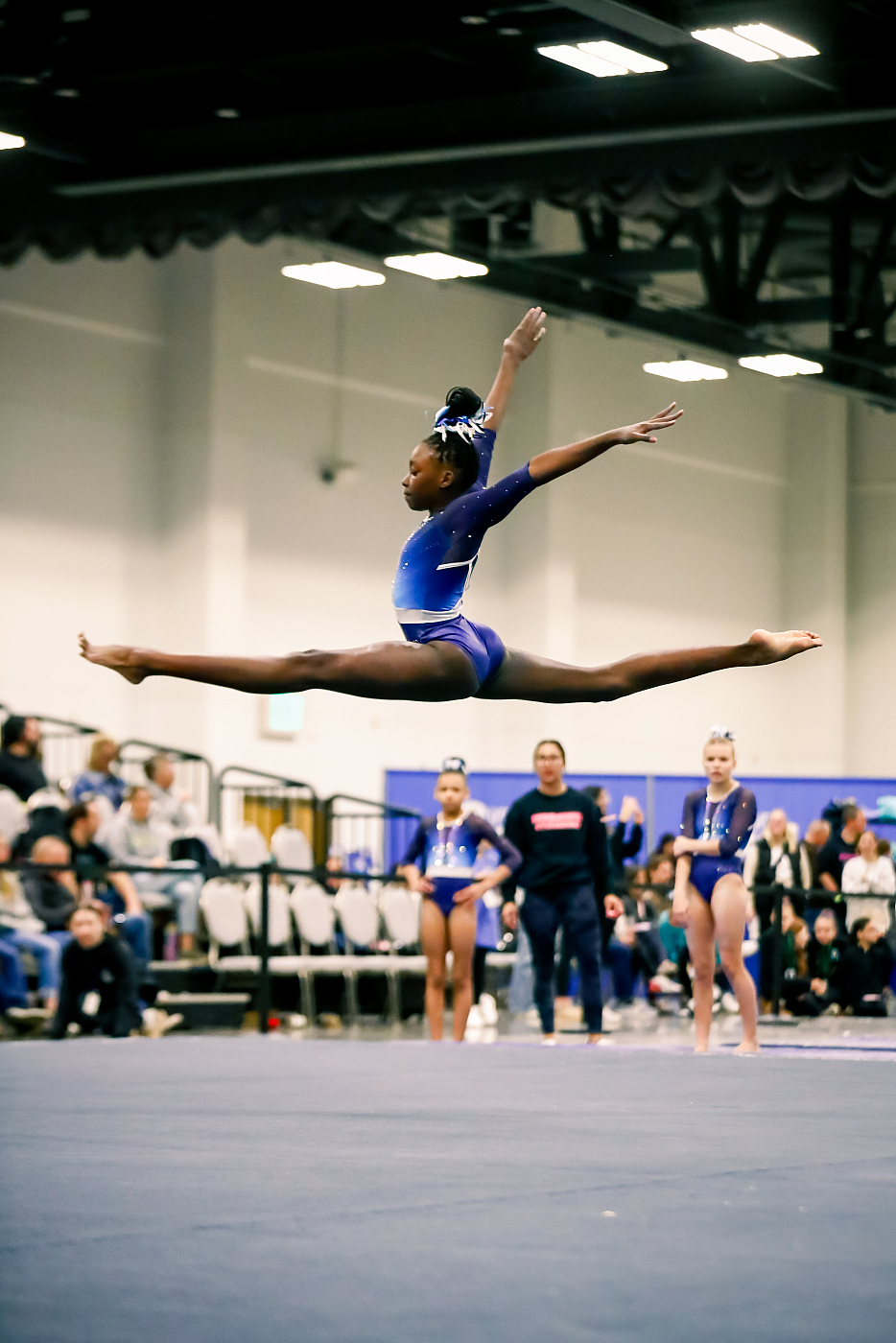 mn gymnast doing split leap on gym floor during event action photo