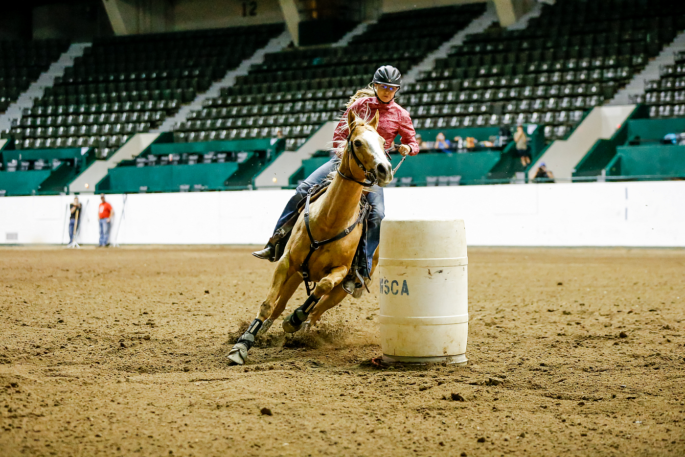 woman riding around barrel tan horse during equestrian event