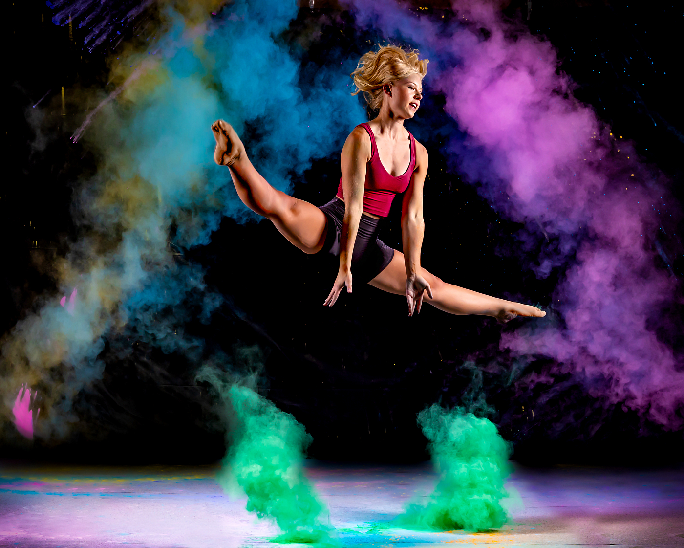 female dancer leaping while tossing multicolored chalk in the air