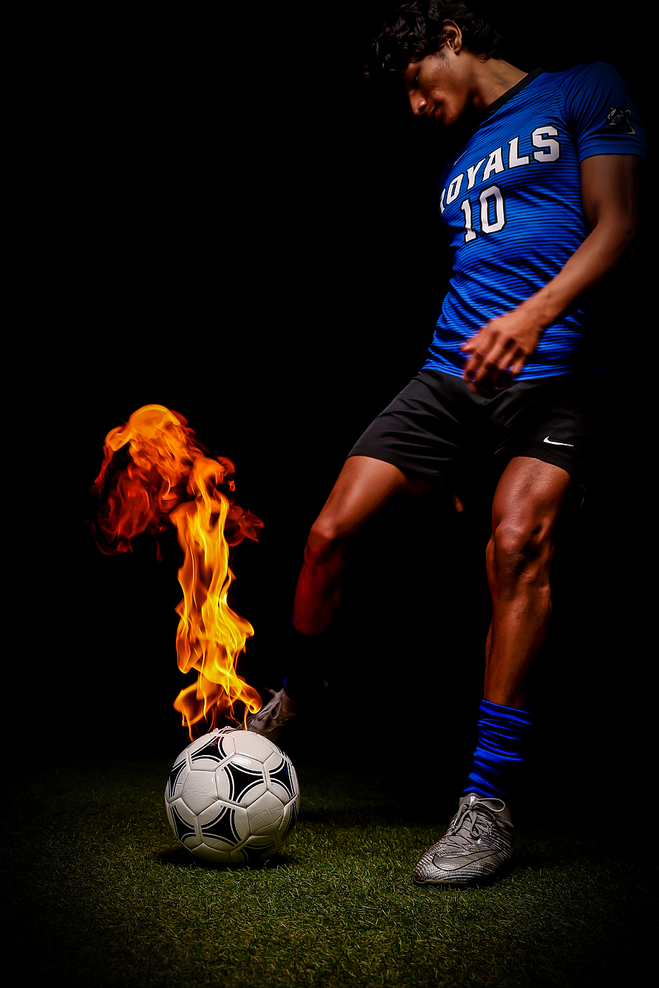 high school boy soccer player kicking ball in flames