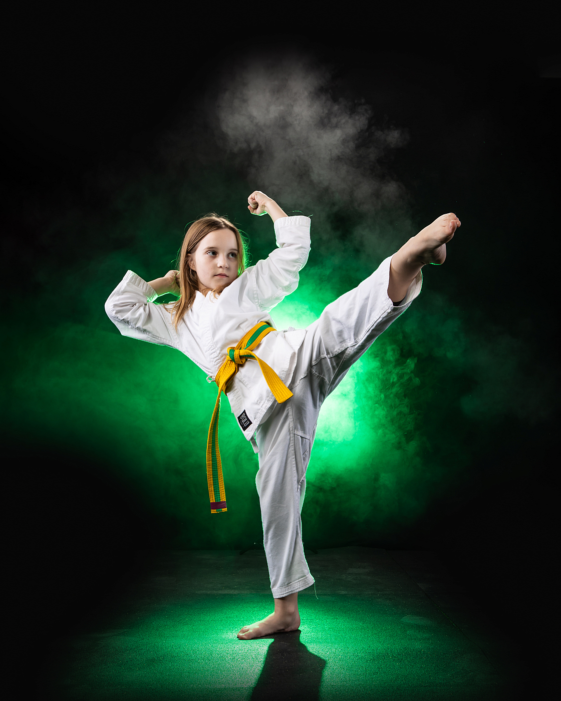 little girl karate kick in air green smoke background